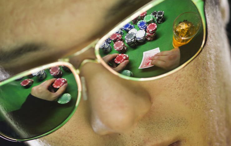 A poker table reflected in the sunglasses of a poker player.