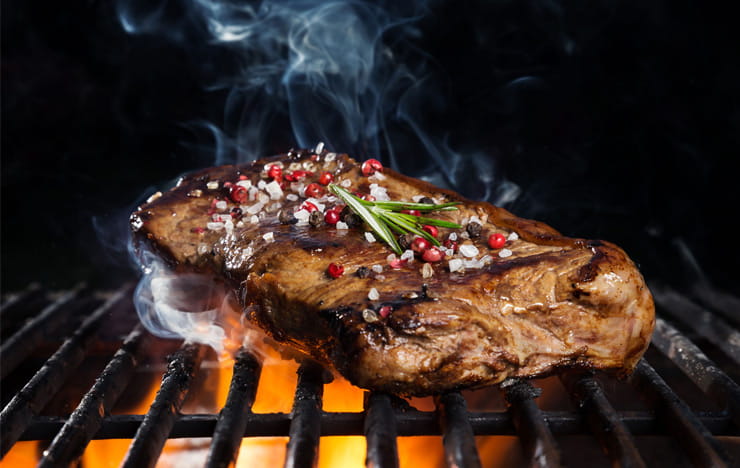 A steak sizzling on a grill.
