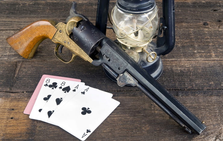 A revolver and cards showing the dead man's hand.