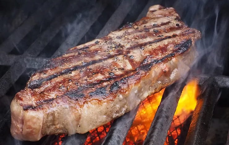 A sizzling steak on a grill.